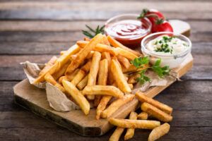 French fries on a cutting board with ketchup and white dip